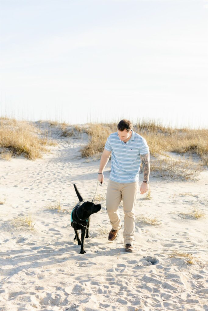 black lab service dog training with handler walking on beach