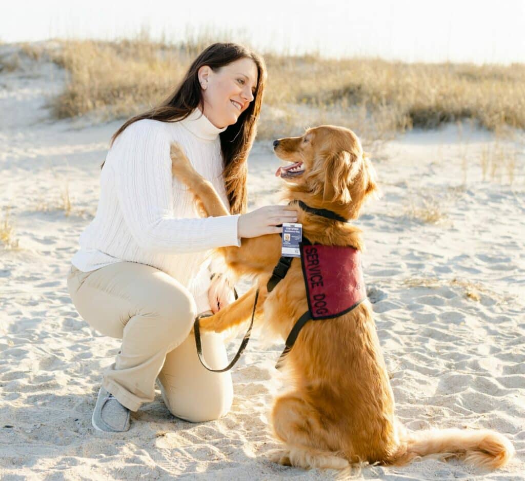 golden retriever service dog sitting on beach with paws up on handler chest