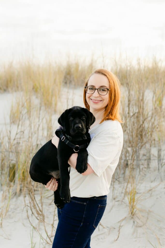 paws4people team member Danielle Cockerham holding black lab puppy