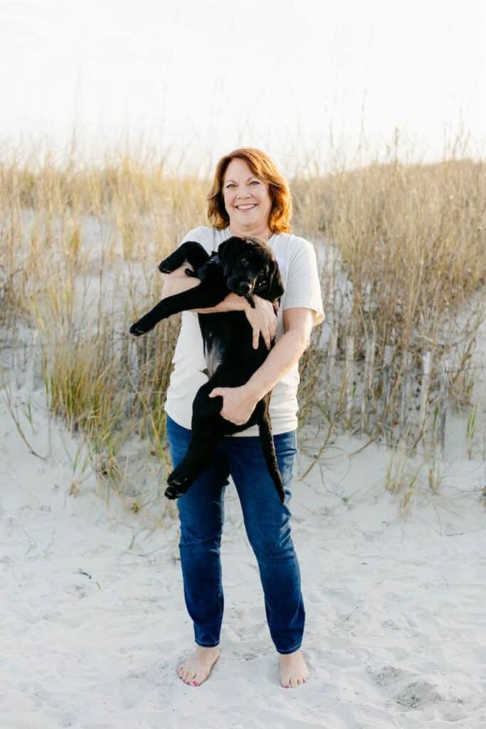 paws4people team member Tracey Rishel holding black lab puppy